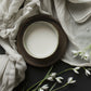 Ceramic bowl with white contents on a dark surface with white flowers