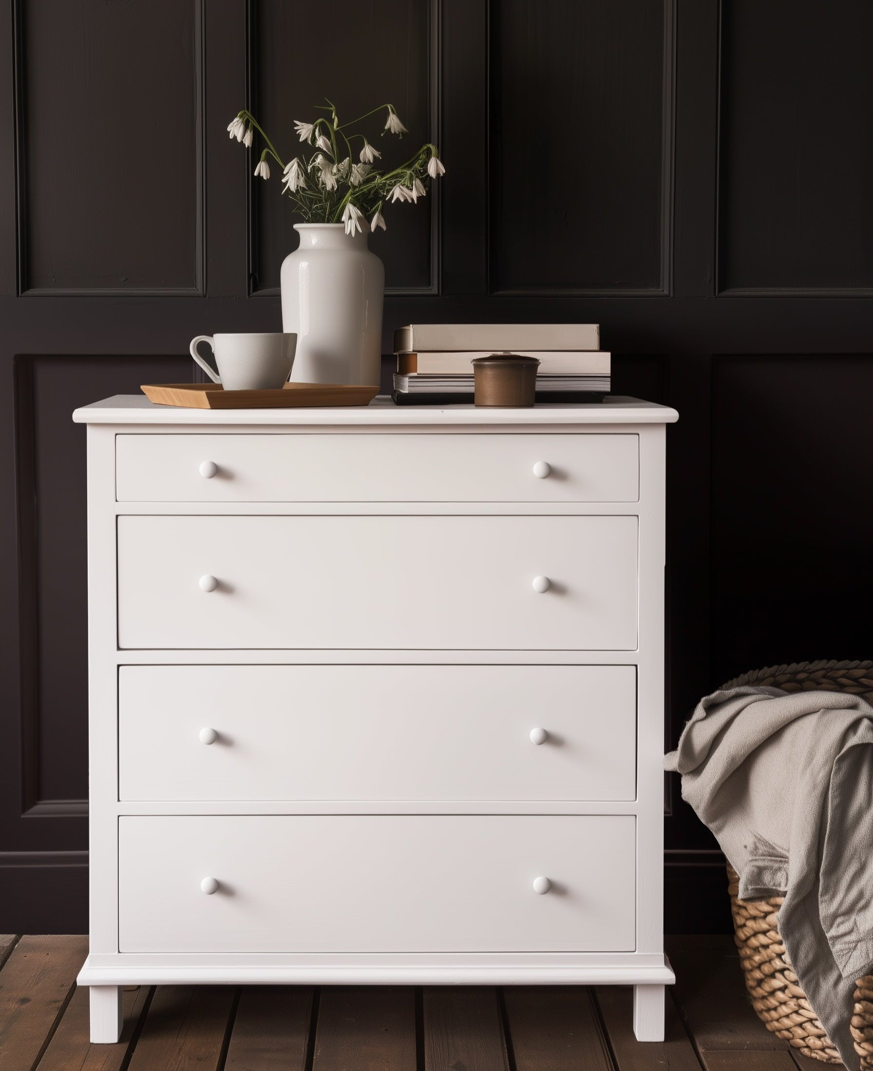 White dresser with decorative items against a dark paneled wall